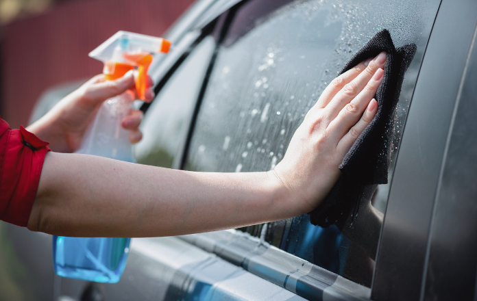 Person cleaning car with quick detailer spray