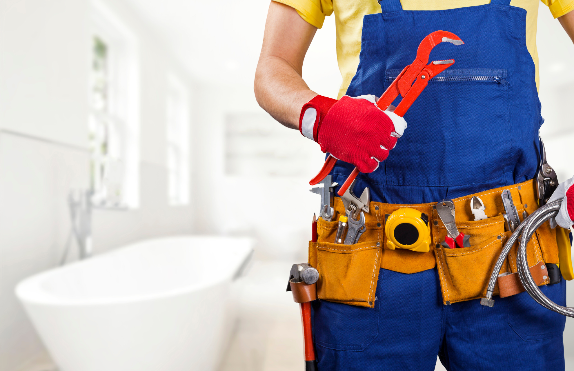 Plumber wearing a tool belt and holding a tool